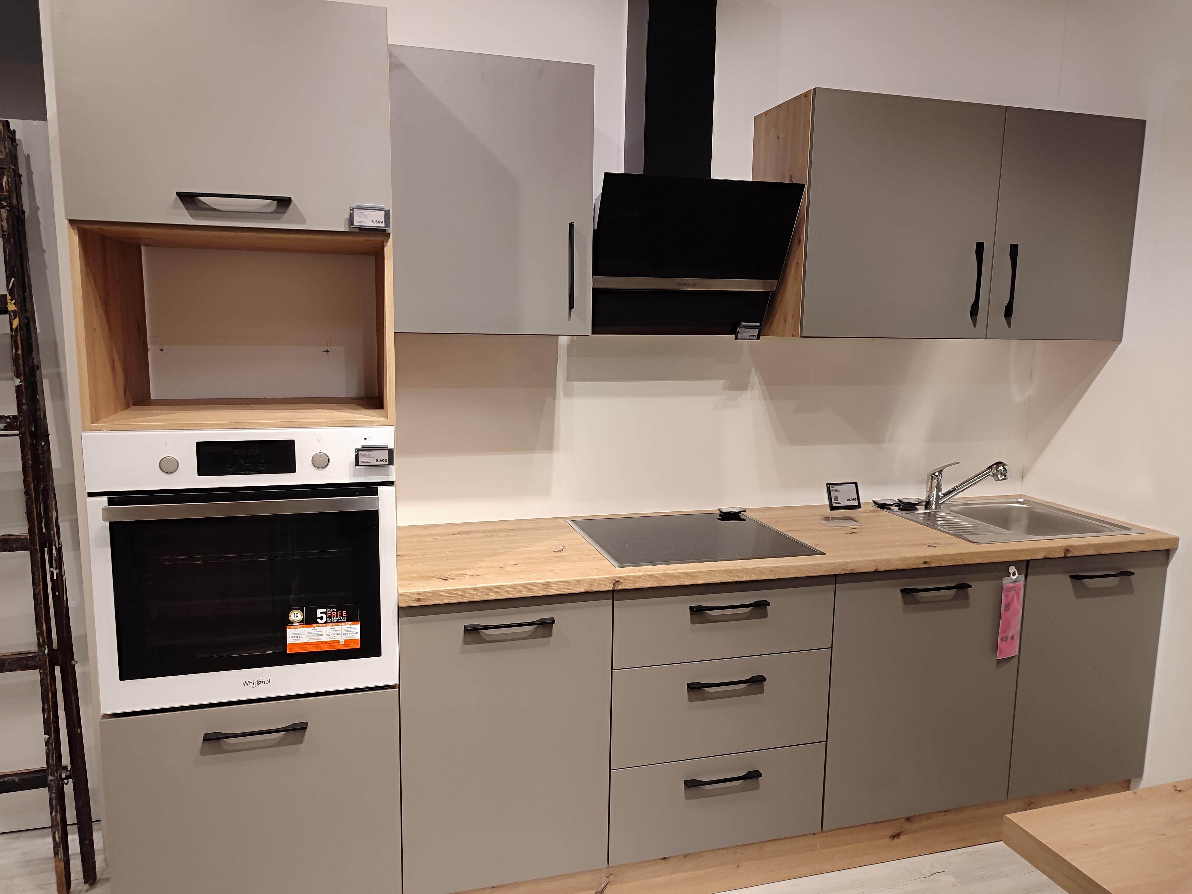 Vzorová kuchyně v showroomu — šedá s dřevěnou deskou