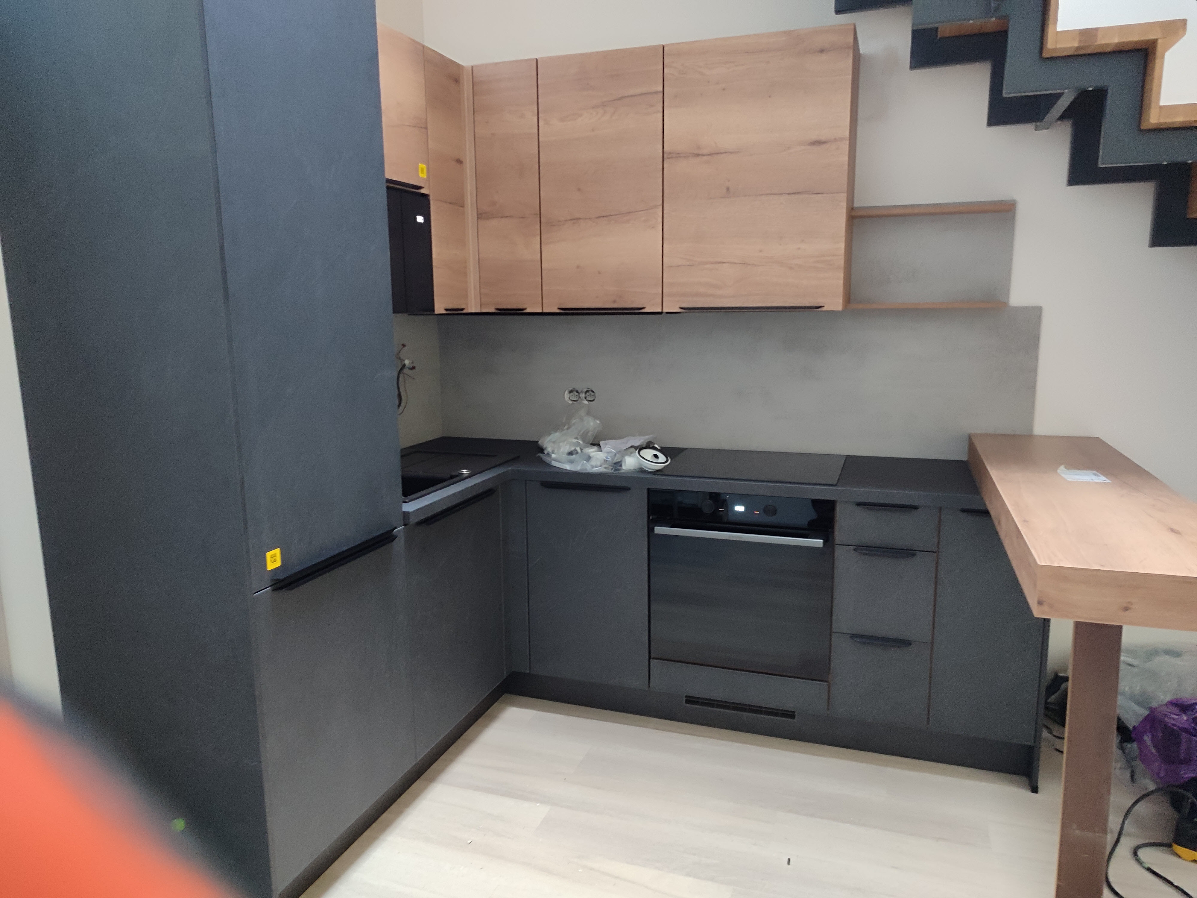 Bílá kuchyně s dřevěnou pracovní deskou a obkladem